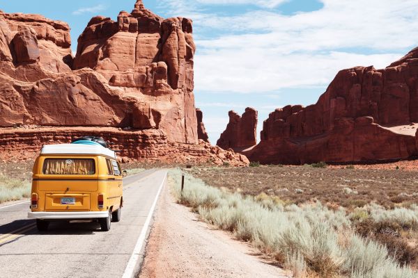gelber Van fährt entlang einer Straße in einem Desert, Reisen in Corona-Zeiten