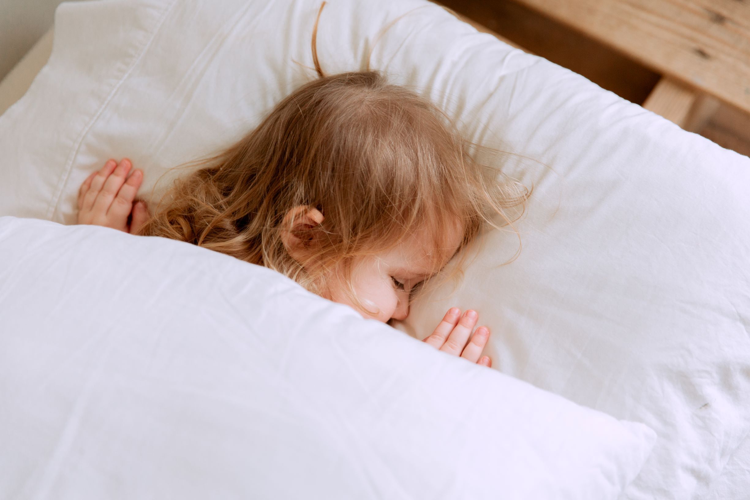 Kind schlafend im Bett zugedeckt, Stillkissen für einen nachhaltigen Start ins Leben